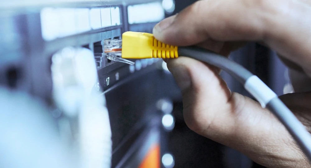 Detail na ruce, které zapojují LAN kabel do serveru